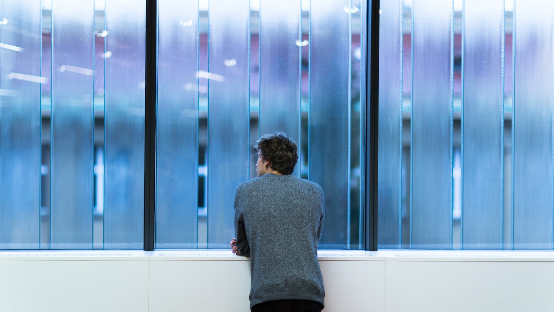 man standing and facing on glass wall
