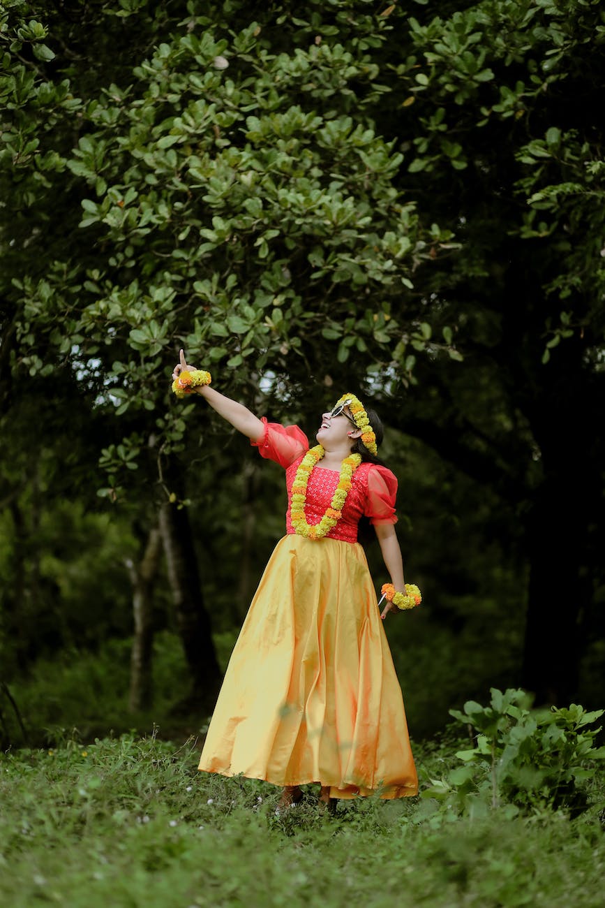 bride in lei on neck and garland on head standing by tree