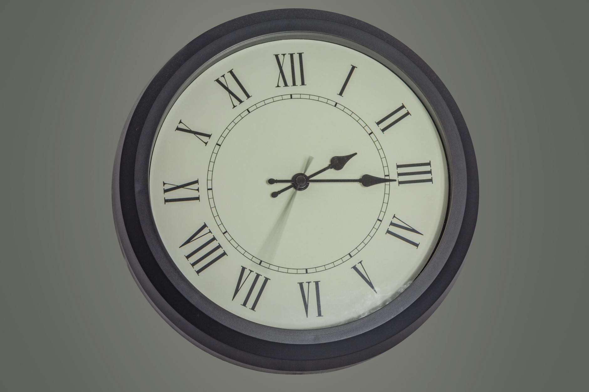round clock hanging on gray wall